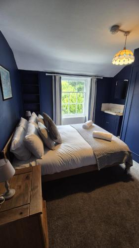 a blue bedroom with a large bed with a window at Beautiful 4BR Georgian house in Wisbech