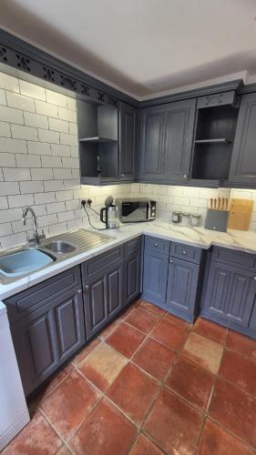 a kitchen with blue cabinets and a tile floor at Beautiful 4BR Georgian house in Wisbech