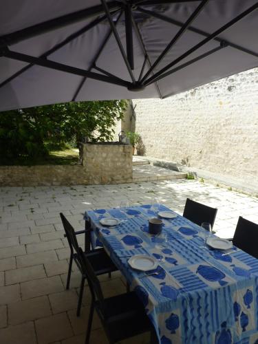 une table bleue et blanche avec des chaises et un parasol dans l'établissement La Maison Blanche, à Dompierre-sur-Mer
