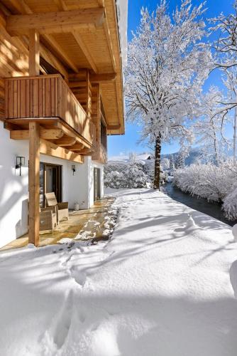 a snow covered yard in front of a house at Riverside Chalet Alpspitze in Garmisch-Partenkirchen