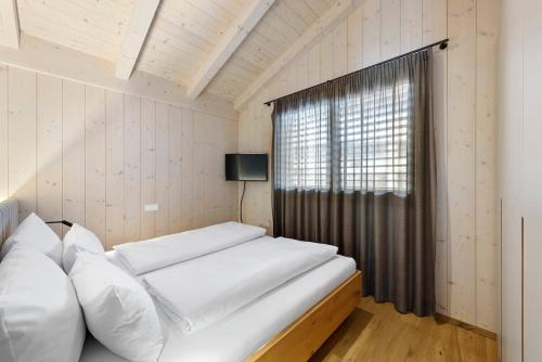 a bedroom with a bed with white pillows and a window at Riverside Chalet Alpspitze in Garmisch-Partenkirchen