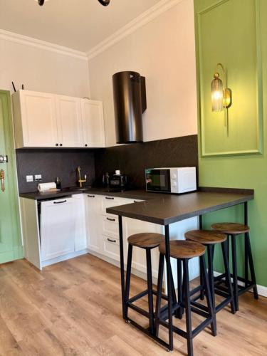 eine Küche mit weißen Schränken und einer Theke mit Stühlen in der Unterkunft Belvedere Old Town with Balcony AC Progres in Toruń
