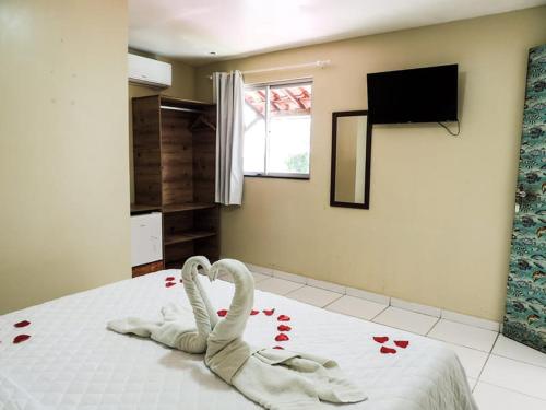 two swans laying on a bed in a bedroom at Pousada vila bela in Porto De Galinhas