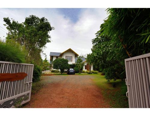 a house with a gate in front of a dirt road at Pvs villa in Bekal