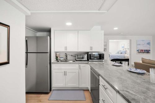 a kitchen with white cabinets and a stainless steel refrigerator at Sprawling Home 1 Mi to Downtown in Harwich