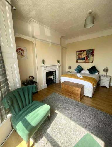 a bedroom with a bed and a chair and a fireplace at 106 Brynmill - Room 1 - Sea views in Sketty