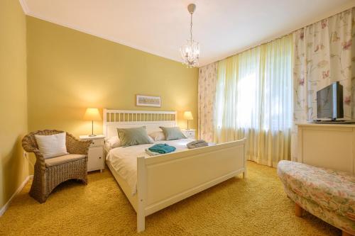 a bedroom with a bed and a chair and a television at Landhaus Hindenburg in Bad Gleichenberg