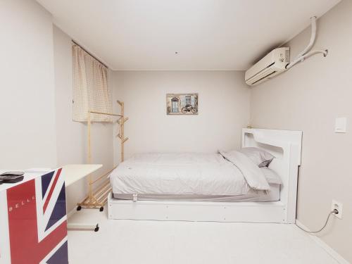 a white bedroom with a bed and a desk at BK Room in Incheon