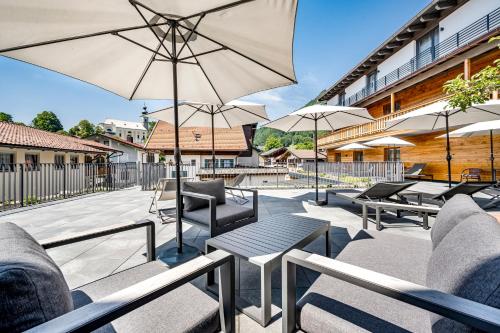 a patio with tables and chairs and umbrellas at Ruhpoldinger Hof - Hotel & Wellness in Ruhpolding