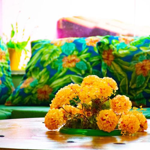 a vase of yellow flowers on a table with a couch at Pousada vila bela in Porto De Galinhas