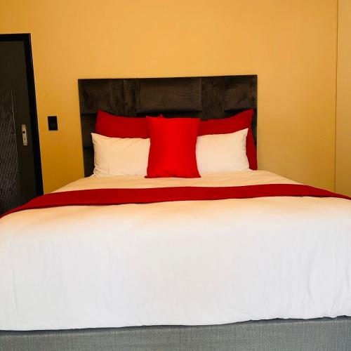 a bedroom with a large bed with red and white pillows at Masithandane lodge in Richards Bay