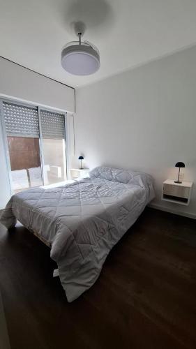a white bedroom with a large bed and a window at Arequito centro in Arequito