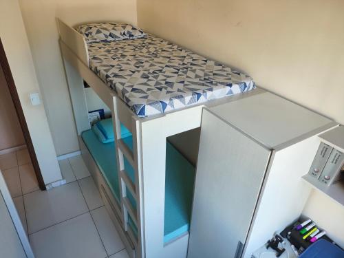 a bunk bed in a small room with a refrigerator at Cobertura Pampulha in Belo Horizonte