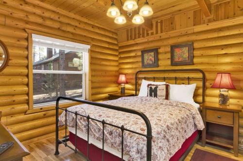 ein Schlafzimmer mit einem Bett in einer Blockhütte in der Unterkunft Cub's Cabin / Charming 3-Bedroom Log Cabin Near Big Bear Lake in Big Bear Lake