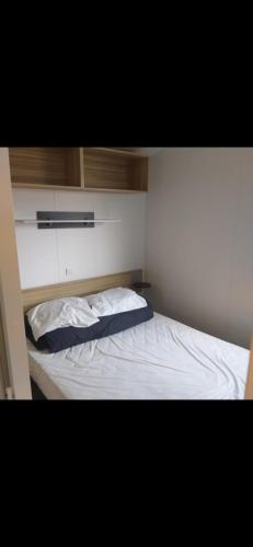 a small bedroom with a bed with white sheets at Mobil-home 3 chambres 6 personnes in Saint-Hilaire-de-Riez