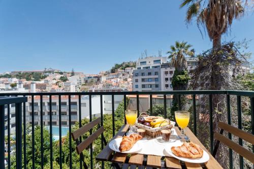 a table with a plate of food and two glasses of orange juice at Castle View Suites in Lisbon