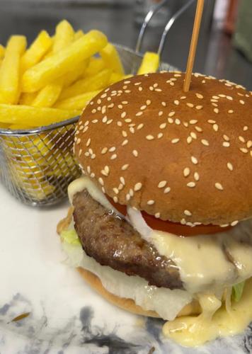 a hamburger with cheese and a basket of french fries at Hotel Restaurant Edelweiss in Mühlen