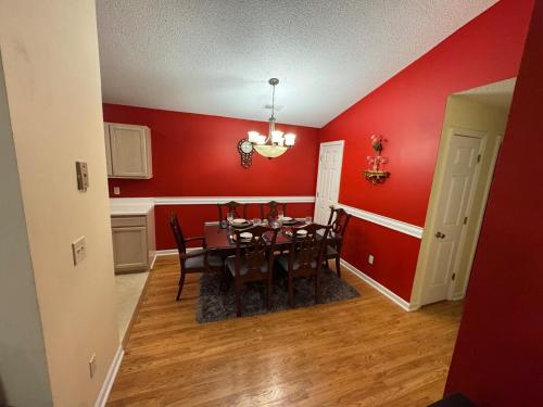 a dining room with a table and red walls at 2Bed 2Bath Cozy Apartment off Guilford college! in Greensboro