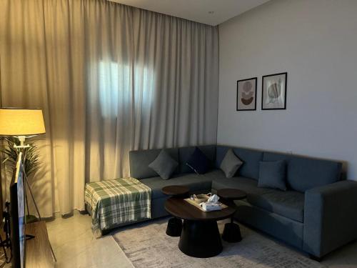 a living room with a blue couch and a table at شقق المها وصول ذاتي in Hafr Al Baten