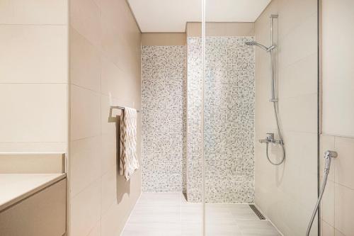 a shower with a glass door in a bathroom at 1BR Yas Marina Apartment - Near Ferrari World in Abu Dhabi