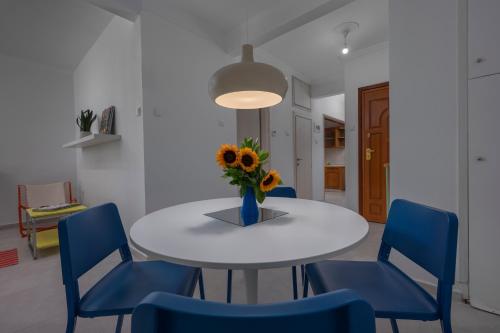 a white table with a vase of flowers and blue chairs at Angel's Urban Up-ART-ment in Thessaloniki