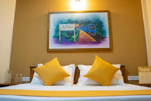 a bed with yellow pillows and a painting on the wall at Winterfell Bandarawela in Bandarawela