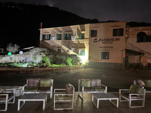 a group of chairs in front of a building at night at Avernum Relais Hotel e Ristorante in Pozzuoli