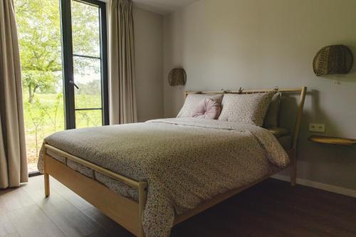 een slaapkamer met een groot bed en een raam bij Gastenverblijf Beekweide - de Notenboom in Voorst