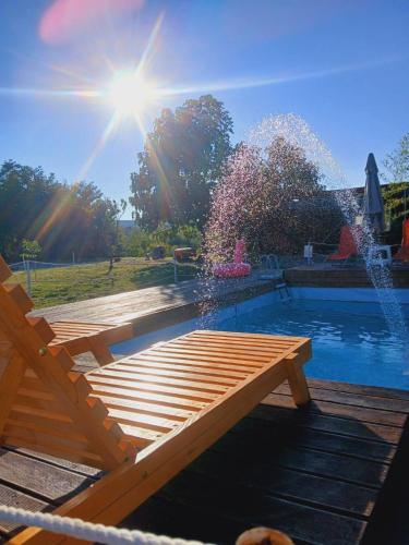 a wooden bench next to a pool with a fountain at Sunny Side Fruska Gora - veliko imanje sa kucom za odmor in Velika Remeta