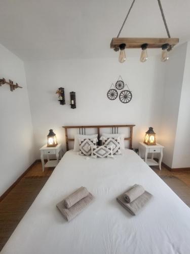a bedroom with a large white bed with two tables at Spring Water House in Olho Marinho