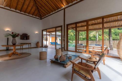 a living room with tables and chairs and windows at Casa Marlim - Trancoso Eco Residence in Porto Seguro