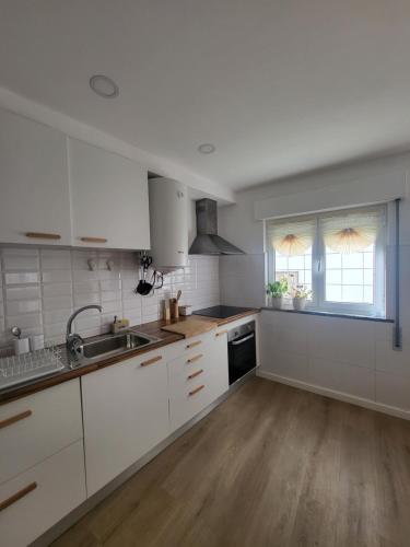 a kitchen with white cabinets and a sink and a window at Spring Water House in Olho Marinho