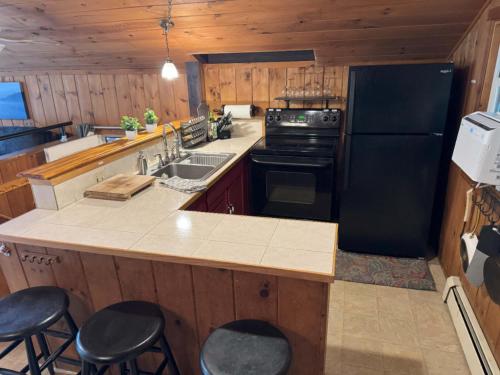 a kitchen with a black refrigerator and a counter with stools at Serene Forest Lodge I Adventure Meets Serenity in Madison