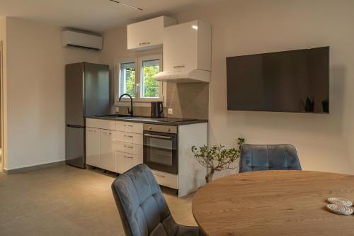 a kitchen with a table and a kitchen with a television at Elonea Villas, Luxury Villas and Studios in Kallikrateia Halkidiki with Garden, Veranda & BBQ in Nea Kalikratia