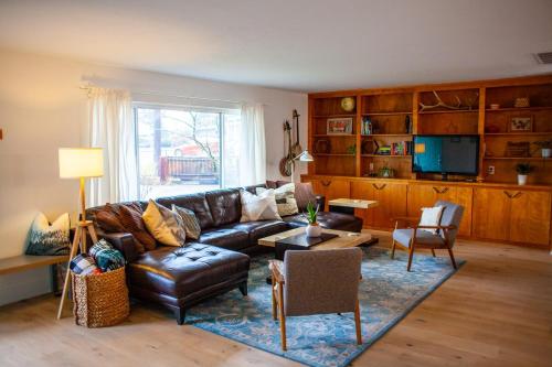 a living room with a leather couch and a tv at Modern Gorge Lodge in The Dalles