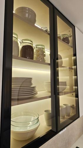 a glass cabinet with plates and bowls in it at Sila apartman Vrnjačka Banja in Vrnjačka Banja