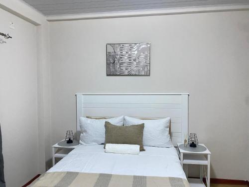 a bedroom with a white bed with two night stands at Wanansha Apartments in Gaborone
