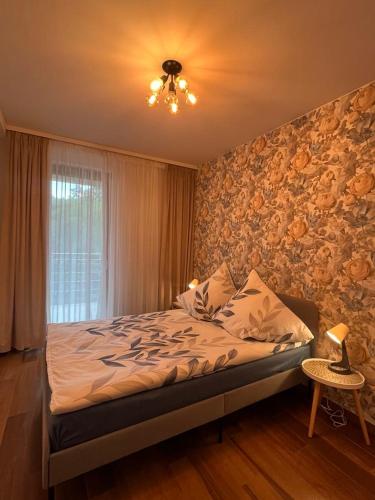 a bedroom with a bed and a wall with flowers at Apartament Sara in Oleśnica