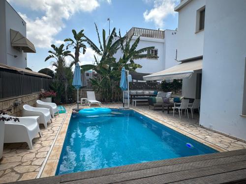 a pool with chairs and umbrellas next to a building at Villa Serenity in Protaras