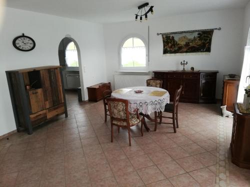 a dining room with a table and chairs and a clock at Villa Lindenpark in Naila