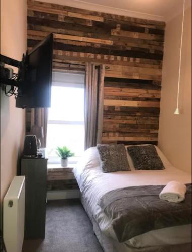 a bedroom with a wooden accent wall and a bed at 106 Brynmill - Room 10 - Sea views in Sketty