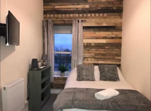 a bedroom with a bed with a wooden wall at 106 Brynmill - Room 10 - Sea views in Sketty