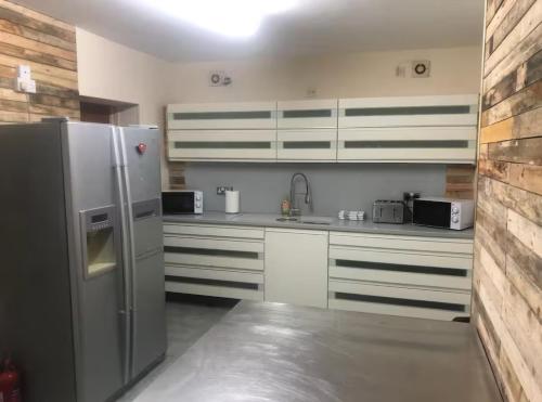 eine Küche mit einem Edelstahlkühlschrank und weißen Schränken in der Unterkunft 106 Brynmill - Room 10 - Sea views in Sketty