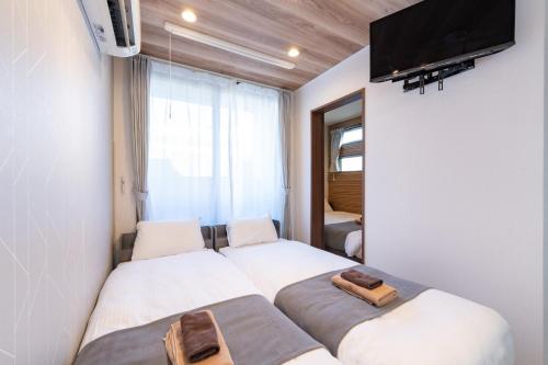 名古屋市にあるRegalist Nagoya Dome - Vacation STAY 19472のベッド2台、壁掛けテレビが備わる客室です。