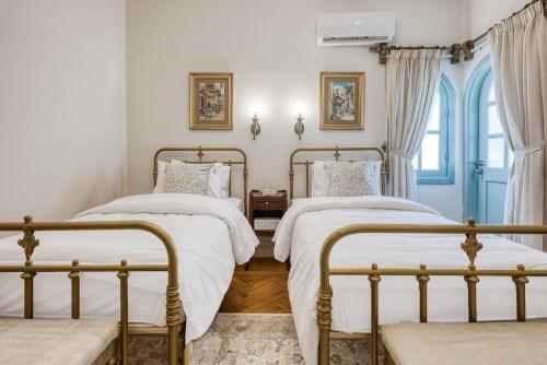 two beds in a bedroom with white walls at Khan Al-Andalus in Cairo