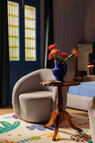 a room with a chair and a table with a vase of flowers at Maison Lezard in Mexico City