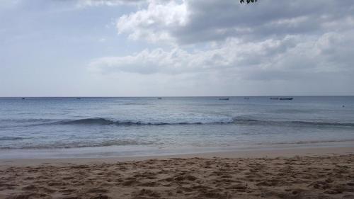 a beach with waves and boats in the ocean at Golden Acre Beach Villa-2 mins walk - Alleynes Bay in Saint James