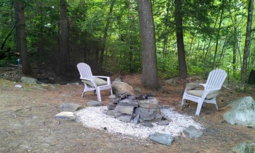 two chairs and a fire pit in the woods at Serene Forest Lodge I Adventure Meets Serenity in Madison