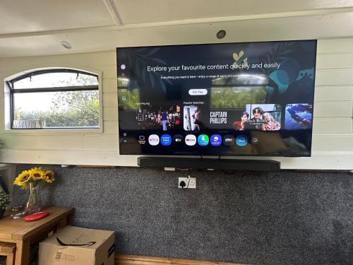 a large flat screen tv on a wall in a room at BrightOwl Waterside Narrowboat Cottage Experience in Thorpe