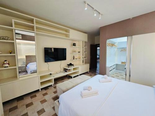 a bedroom with a large white bed and a television at Spacious Central Apartment in Tirana